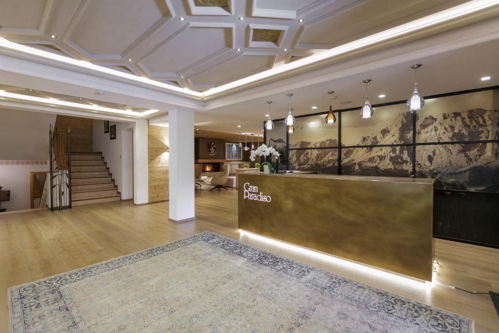 Hotel reception area with a brass front desk, warm lighting, and a large patterned rug in a modern lobby.