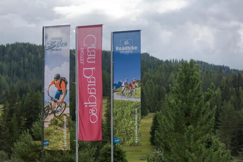 Three tall vertical banners advertising bike holidays set against a forested hillside and cloudy sky.